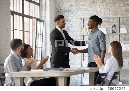 Smiling executive congratulating African American employee, shaking hands Smiling executive congratulating African American employee, shaking hands 66022245
