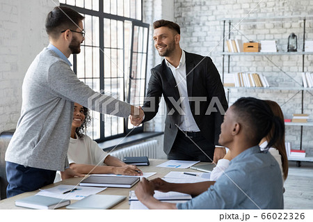 Smiling business partners shaking hands at group negotiations 66022326