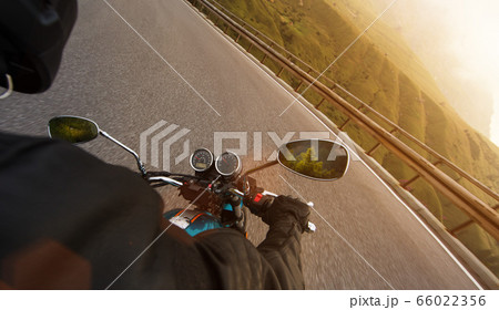 Motorcycle driver riding in Alpine highway, 66022356
