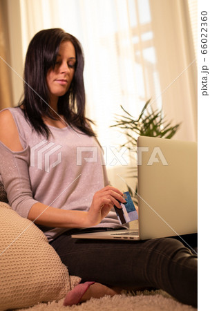 Woman is holding credit card and using laptop 66022360