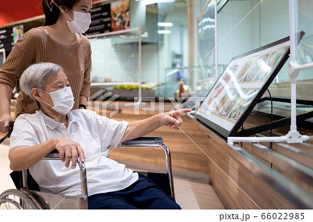 Senior woman in a mask,old elderly choosing menu food for lunch in food court,reducing stress by eating and shopping at mall,bored staying at home for a long time after Coronavirus quarantine,Covid-19 66022985