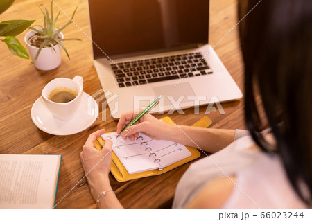 Woman is using laptop computer and note pad. 66023244