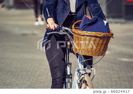 A girl rides a bicycle along a city street, with a 66024417