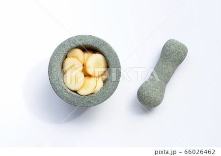 Fresh galangal slices in stone mortar with pestle 66026462