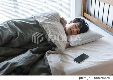 ベッドにスマホを置いて眠る若い男性 ベッドにスマホを置いて眠る若い男性 66026820