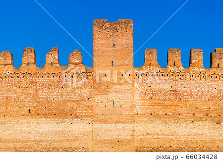 Old brick wall of medieval Italian fortress against the blue sky 66034428