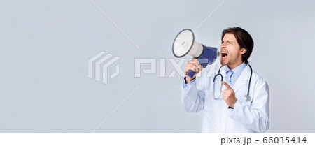 Angry male doctor shouting with megaphone at copy space on light background 66035414