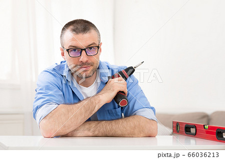 Man Holding Electric Drill Sitting Looking At Camera At Home 66036213