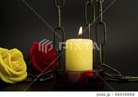 Burning yellow candle, chain and two roses 66036668
