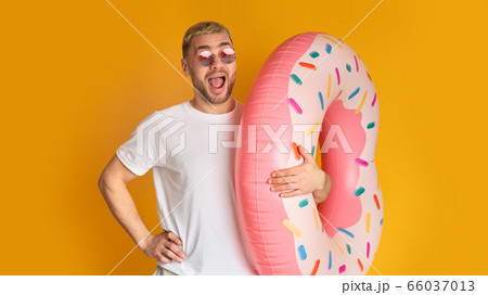 Happy male in sunglasses holds swimming circle Happy male in sunglasses holds swimming circle 66037013