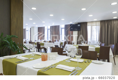 Tableware in hotel restaurant. Room with luminous lit Tableware in hotel restaurant. Room with luminous lit 66037020