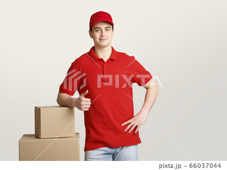 Fast delivery. Courier leans on boxes and shows sign perfectly with his hand 66037044