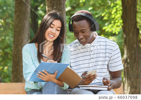 Two college mates preparing for lectures, studying together outdoors 66037098