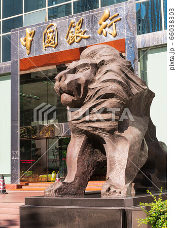 The statue of a lion at the entrance to a Chinese bank. The inscription above the door: "Bank of China." The statue of a lion at the entrance to a Chinese bank. The inscription above the door: "Bank of China." 66038303