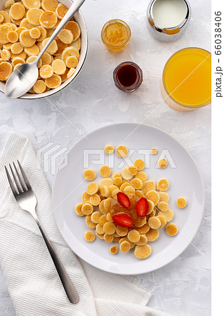 Tiny mini pancake cereal. Home made breakfast with raspberries, jam and juice on gray background 66038406