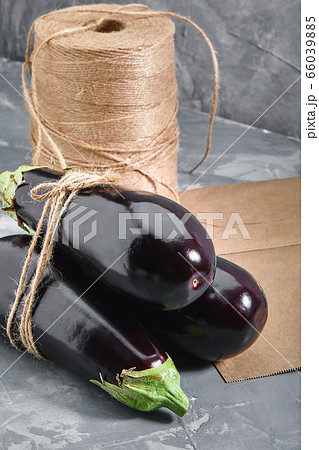 Eggplant on a gray background, behind paper bags and heather for packaging. Vegetable delivery, photo for online stores with delivery. 66039885
