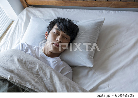 ベッドで眠る若い男性 66043808