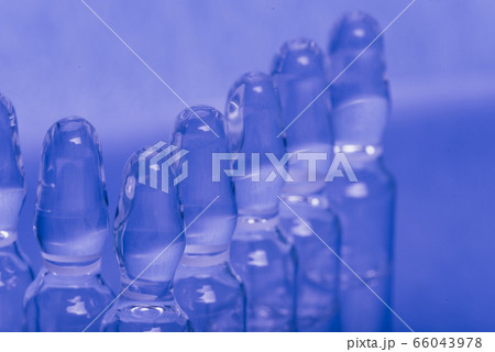 Glass medical ampoule vial for injection. Medicine is liquid sodium chloride with of aqueous solution in ampulla. Close up. Bottles ampule multicolor. Glass medical ampoule vial for injection. Medicine is liquid sodium chloride with of aqueous solution in ampulla. Close up. Bottles ampule multicolor. 66043978