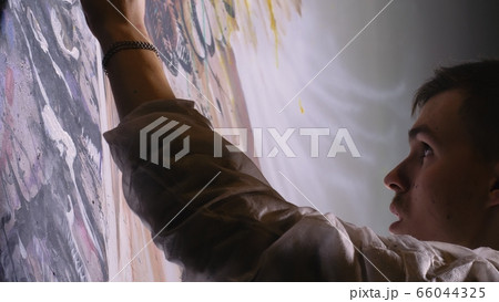 Artist designer draws an eagle on the wall. Craftsman decorator paints picture with acrylic oil color. Painter painter dressed in paint coat. Indoor. Artist designer draws an eagle on the wall. Craftsman decorator paints picture with acrylic oil color. Painter painter dressed in paint coat. Indoor. 66044325