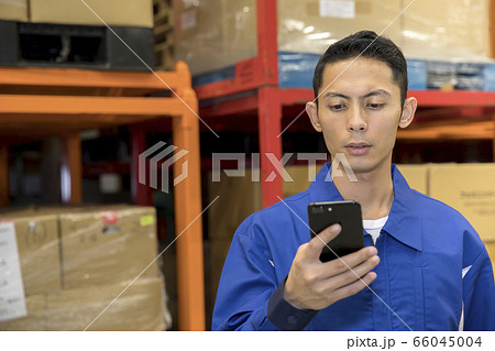 物流倉庫でスマホの操作をする作業員男性の写真素材