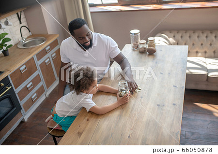 Dark-skinned bearded man talking to his son about saving money Dark-skinned bearded man talking to his son about saving money 66050878