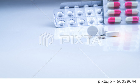 White tablets pills on blurred white-pink capsules 66059644
