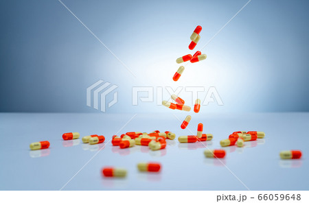 Yellow-orange capsules pill falling down on white Yellow-orange capsules pill falling down on white 66059648