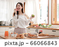 Young asian woman eat red and green apples with cheerful mood in the morning kitchen. 66066843