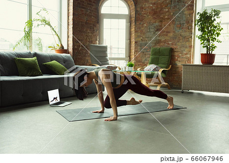 Sporty young woman taking yoga lessons online and practice at home 66067946