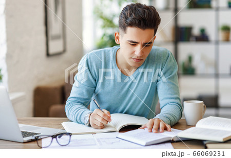 Ethnic freelancer making notes at home. Ethnic freelancer making notes at home. 66069231