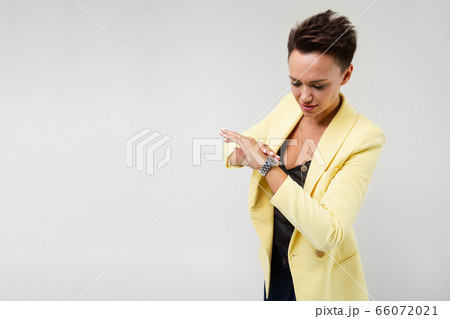 Handsome woman in yellow blazer and black dress looking at time isolated on white background 66072021