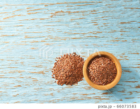 flax seeds spill out of a wooden bowl on a table, flax seeds spill out of a wooden bowl on a table, 66073583