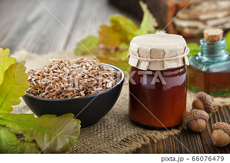 Oak bark in ceramic bowl, jar of salve or balm. 66076479