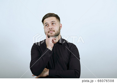 Serious Male Holds Forefinger To His Face And Thinks Serious Male Holds Forefinger To His Face And Thinks 66076508