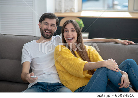 Man in white tshirt and girl in yellow sweater on sofa Man in white tshirt and girl in yellow sweater on sofa 66084910
