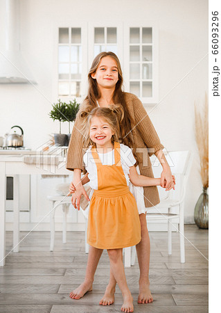 Two sisters play in a bright, stylish kitchen. Beautiful interior. Two sisters play in a bright, stylish kitchen. Beautiful interior. 66093296