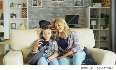 Little girl laughing while watching a video on smartphone 66094487
