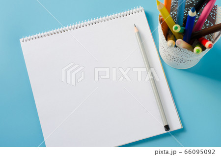 Blank notebook and set of colorful pencils on blue background. Paper background. Blank notebook and set of colorful pencils on blue background. Paper background. 66095092