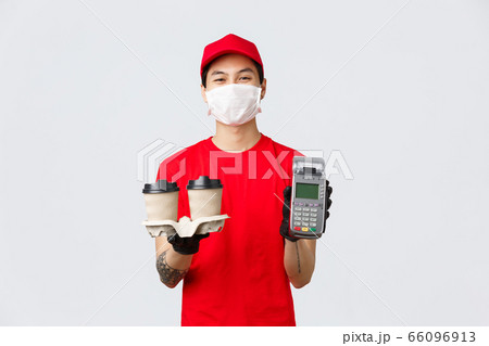 Contactless delivery, safe purchase, shopping during coronavirus concept. Smiling nice courier in medical mask and gloves, employee in fast-food deliver showing POS terminal and bring coffee customer 66096913