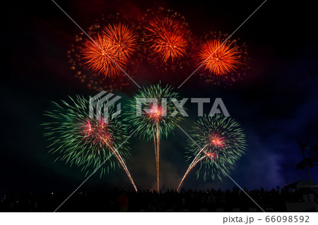 Crowd looks holiday fireworks in dark evening sky. Crowd looks holiday fireworks in dark evening sky. 66098592