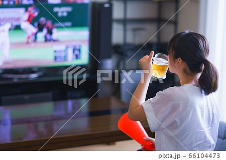 家でスポーツをテレビ観戦する若い女性のイメージ プロ野球の動画配信サービス の写真素材