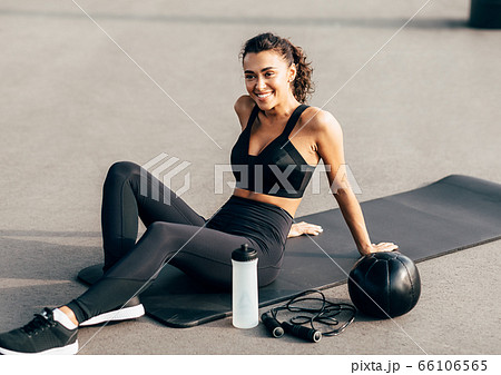 Beautiful sportswoman resting on a mat after exercising outdoors 66106565