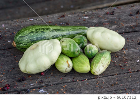 Zucchini, pattypan squash, cucumbers lie on the wooden table 66107312