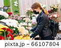 girl during pandemic illness chooses a gift in a flower shop. The concept of the holiday and the purchase of a bouquet during the coronavirus 66107804