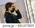 Portrait of a young girl in a medical mask who chooses glasses for herself in an optics store. The concept of poor vision among patients 66107805