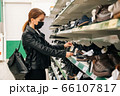 A young Caucasian girl in a medical black mask chooses clothes, shoes products in the supermarket. The concept of social distance and 66107817