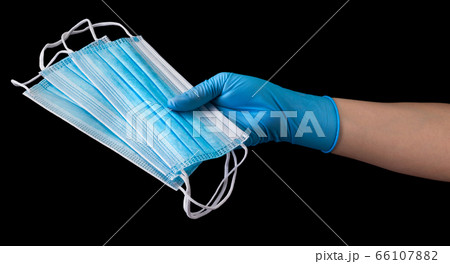 Doctor's hand in medical gloves holding a pile of masks isolated on black Doctor's hand in medical gloves holding a pile of masks isolated on black 66107882