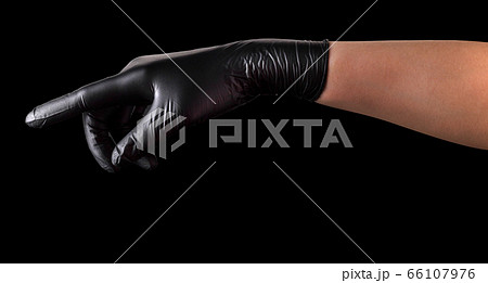 Hand in black gloves with index finger pointing or touching something on black 66107976