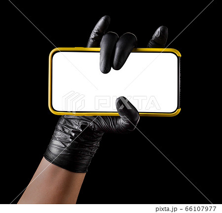 Hand in black glove holding mobile phone with blank screen isolated on black Hand in black glove holding mobile phone with blank screen isolated on black 66107977