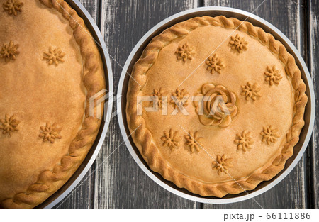Two sweet potato pies with edible decorations on top standing on the wooden table 66111886